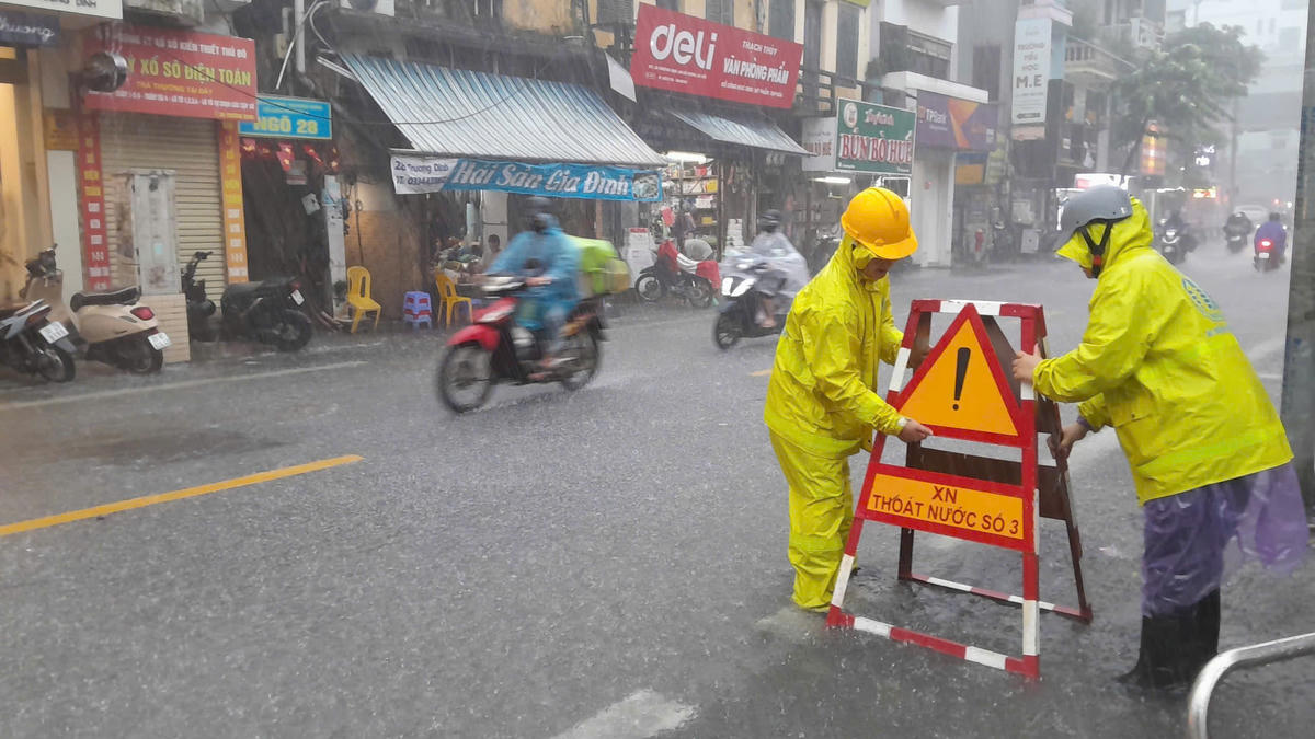 Các công nhân làm việc trong thời tiết mưa lớn.