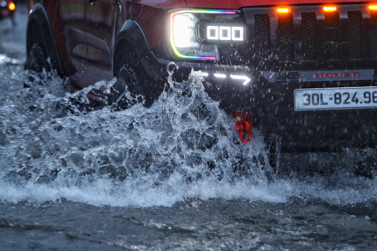 Xe ô tô di chuyển, tạo ra các sóng nước bắn tung toé.