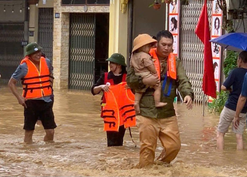 Công an giao thông giúp người dân ở phường Yên Bái đến nơi an toàn. Ảnh: Trần Thanh.