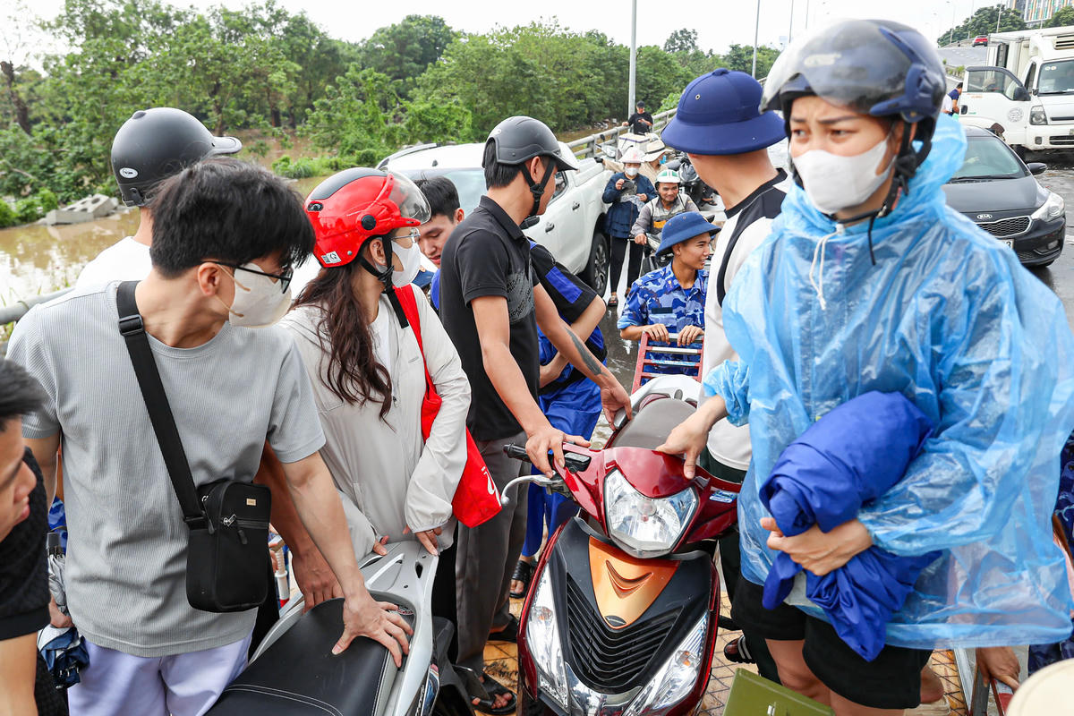 Hàng chục chiến sĩ Cảnh sát biển cùng nhau đưa người dân qua vùng nước ngập.