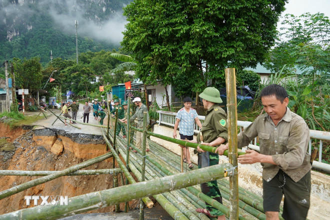Người dân và chính quyền đã kịp thời khắc phục sự cố đầu Cầu Sơn Thủy trên Quốc lộ 16 tại lý trình Km89+580 tại bản Chung Sơn bị hư hỏng nặng chân, mố cầu, và bị sập hoàn toàn mặt đường nhựa dài hơn 10 mét. (Ảnh: TTXVN phát)