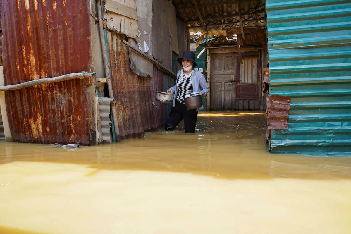 Nước ngập cao gần 1m, chị Sáu tranh thủ đi nấu cơm cho gia đình.