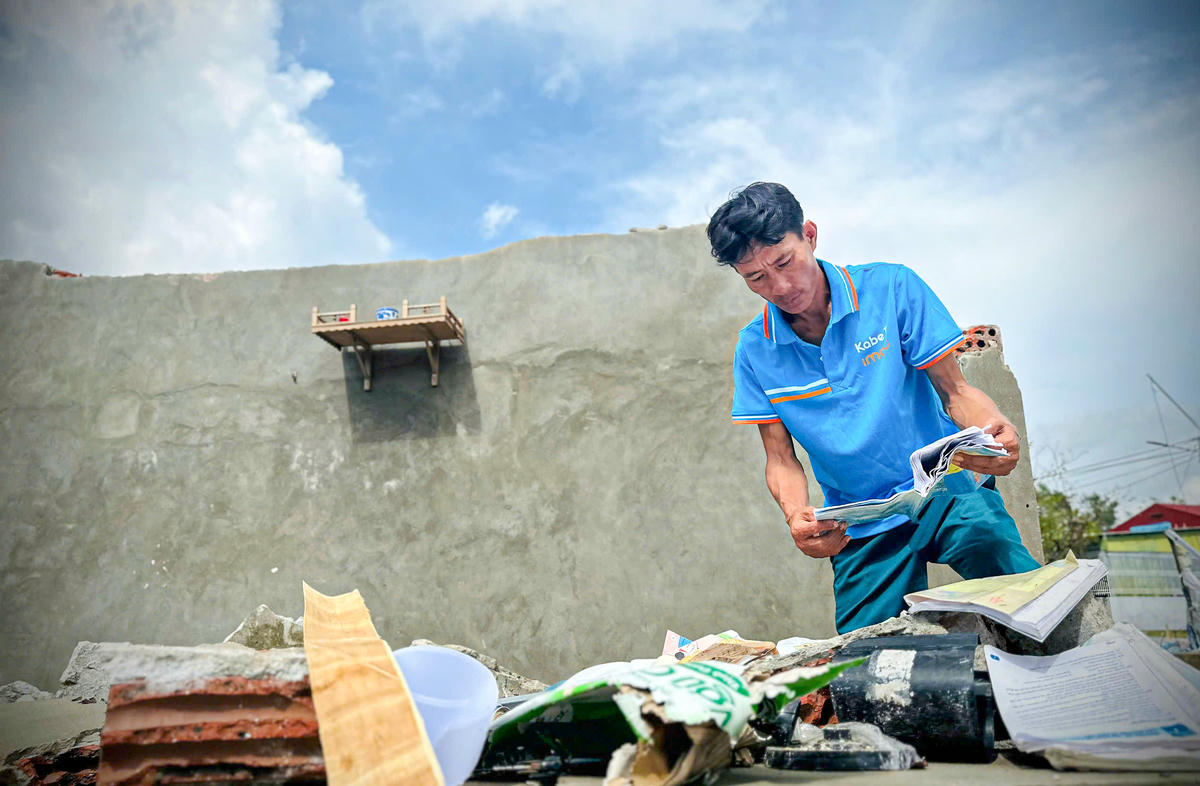 Anh Nam lặng lẽ nhặt từng cuốn sách vở ướt nhão của con đem ra hong. Ảnh: cẩm Kỳ