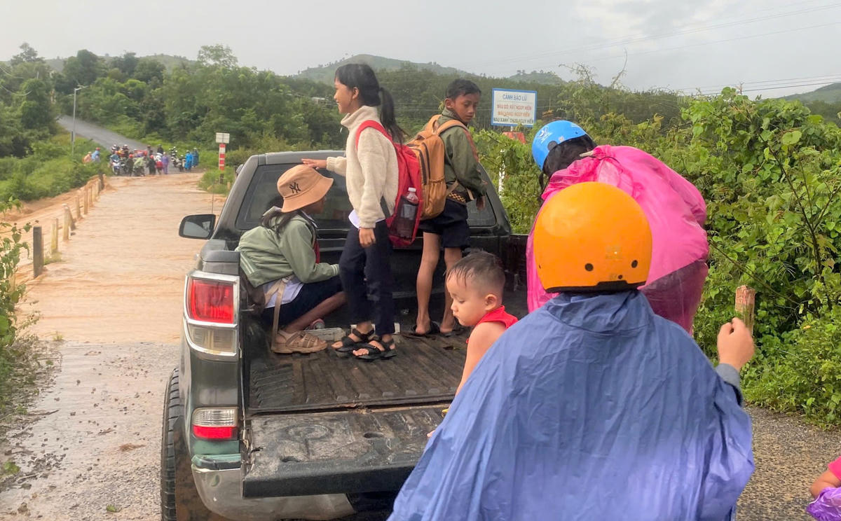 Chị Y
Huen (mắc áo mưa) đang đưa con lên xe để qua cầu Cầu tràn đoạn qua làng Khúc Na. Ảnh: NVCC.