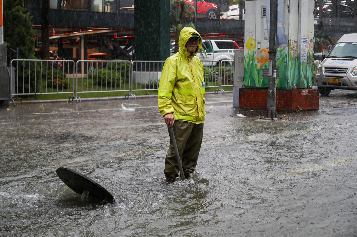 Công nhân thoát nước dầm mưa mở cống thoát nước.