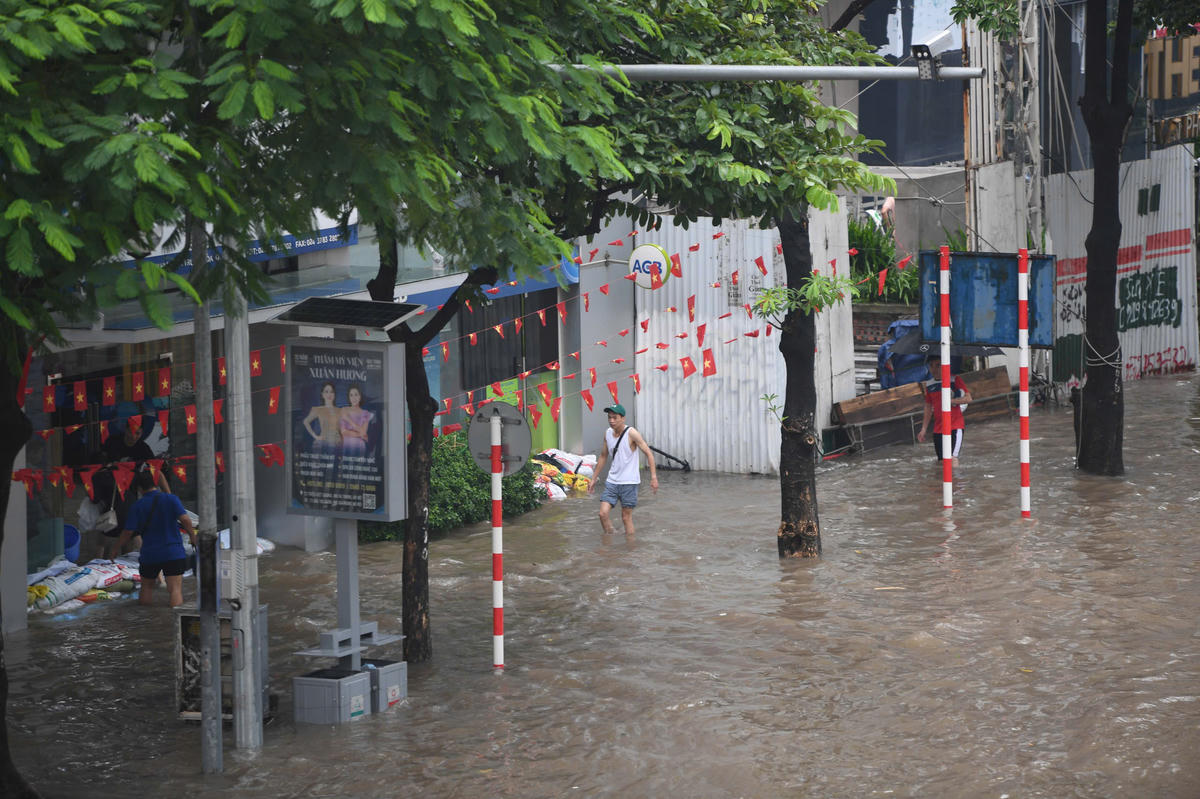 Nhiều nhà mặt phố be bờ bao, tát nước, giảm nước ngập trên đường tràn vào nhà trên phố Trần Duy Hưng.