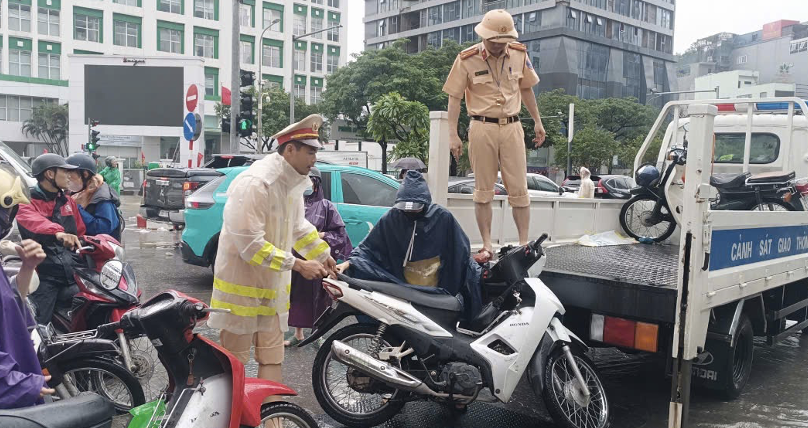 CSGT Hà Nội dùng xe chuyên dụng đưa người dân qua khu vực ngập nghi bị dò điện.