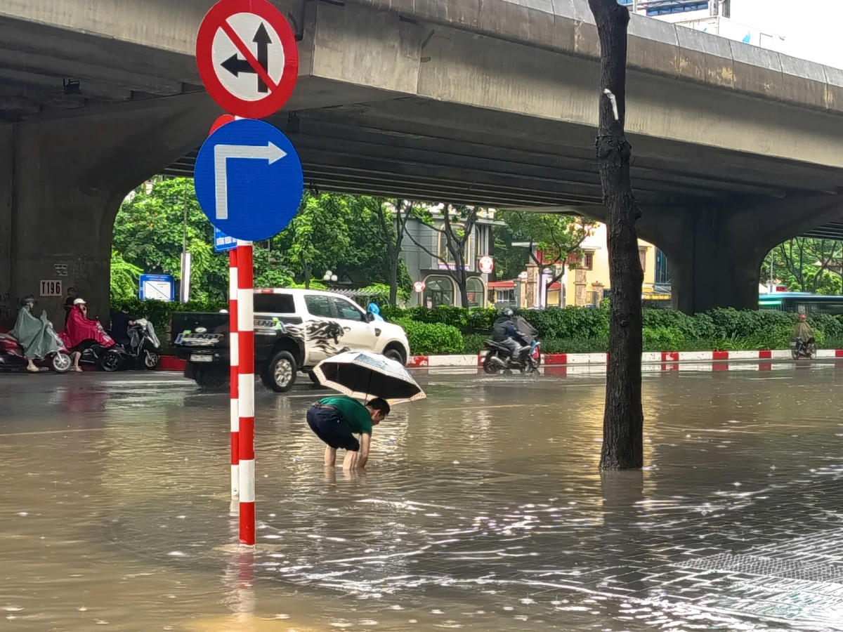Người dân phải đội mưa để khơi thông cống nước.

