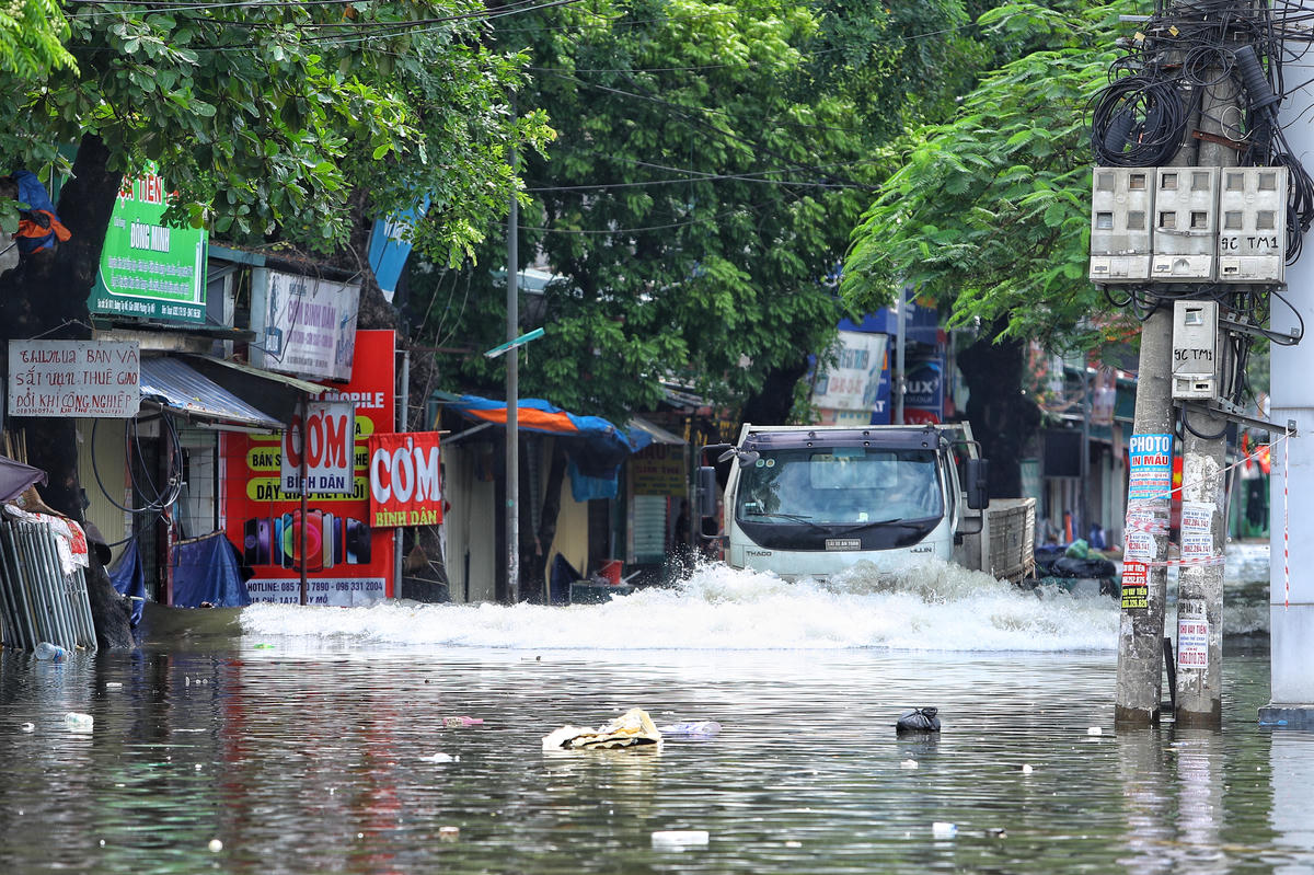 Xe tải phóng nhanh đi qua vùng ngập, tạo thành các sóng nước ập vào nhà dân.