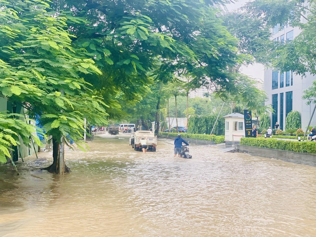 10h sáng 8/10 Tuyến phố Trương Công Giai vẫn ngập, người dân đi lại khó khăn. Ảnh: Vũ Mạnh.