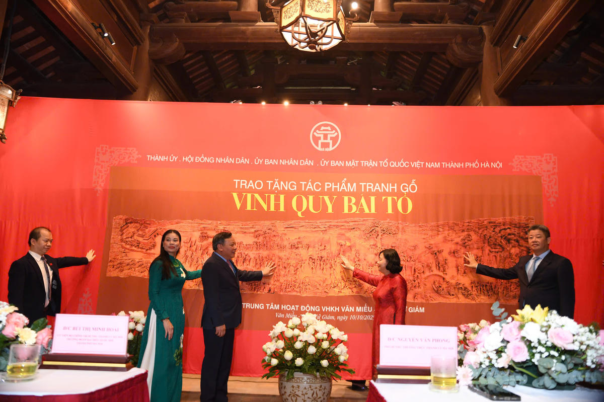 Các đại biểu thực hiện nghi thức trao tặng bức tranh gỗ “Vinh quy bái Tổ”. Ảnh: Phạm Sỹ.