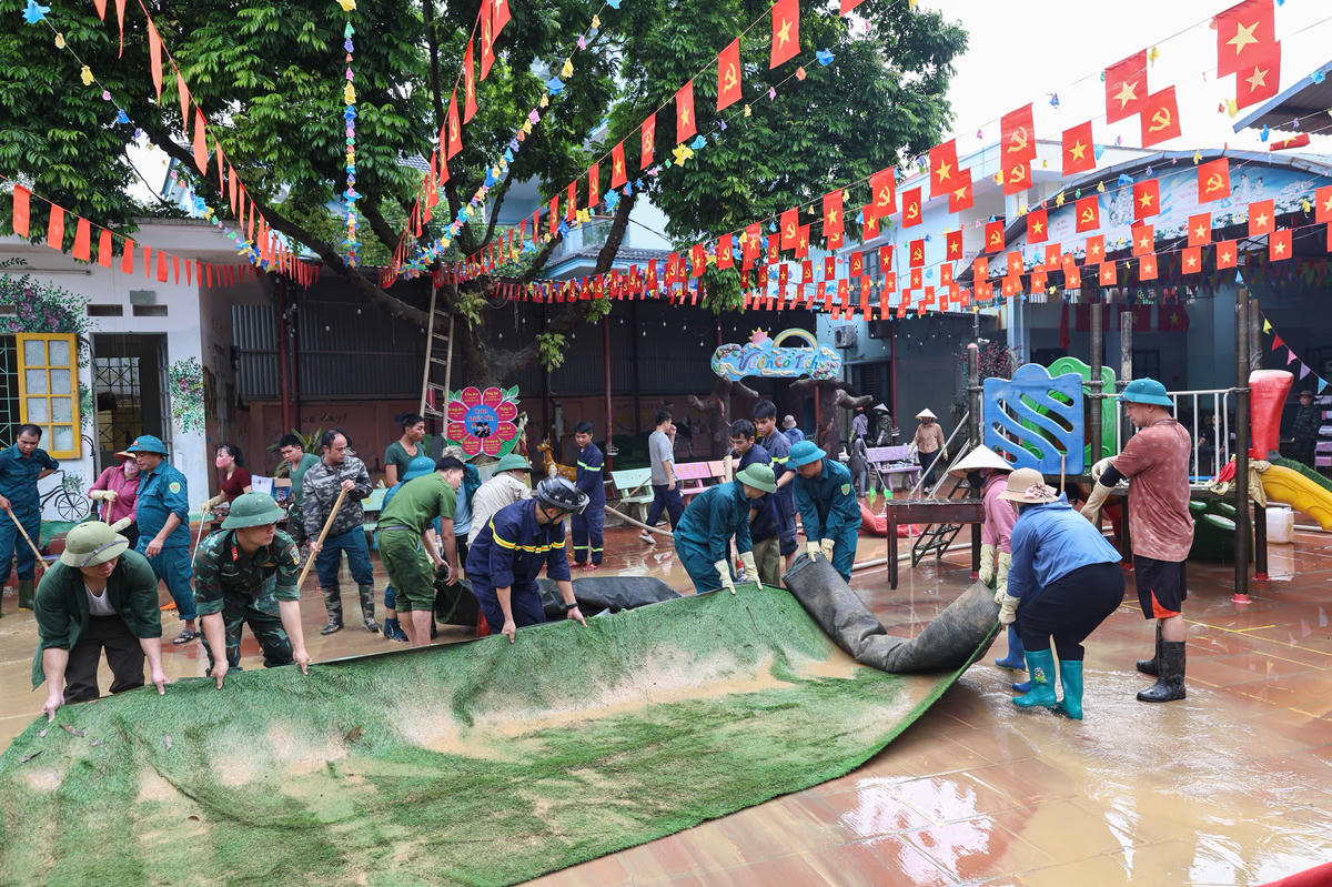 Lực lượng chức năng cùng người dân dọn dẹp tại các trường học. Ảnh: Quang Vinh.