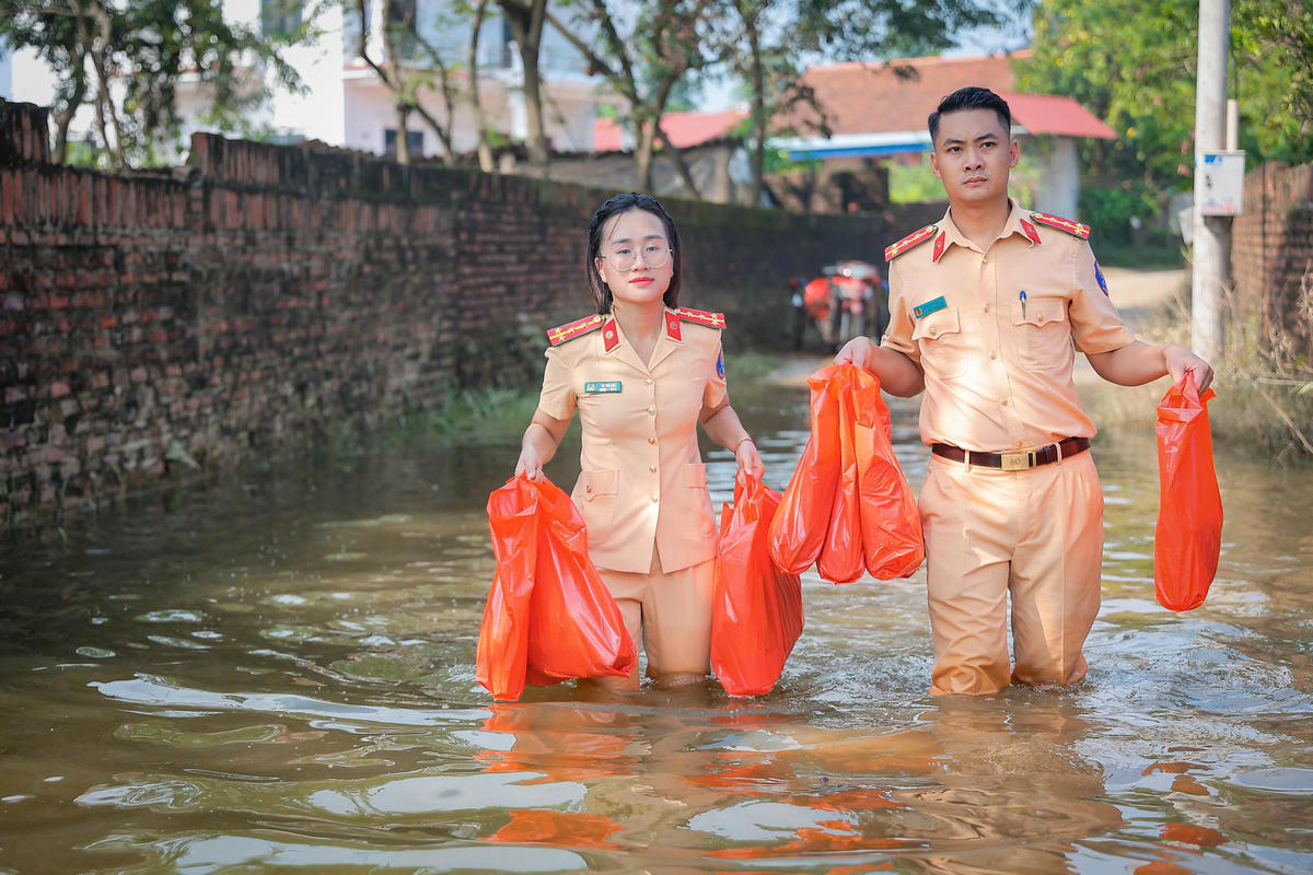 Để việc hỗ trợ diễn ra nhanh chóng, các chiến sĩ CSGT chia nhau, lội nước đến từng ngõ nhỏ trao quà.