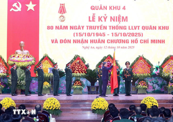 Tổng Bí thư Tô Lâm gắn Huân chương Hồ Chí Minh lên lá cờ truyền thống của Quân khu 4. (Ảnh: Thống Nhất/TTXVN).
