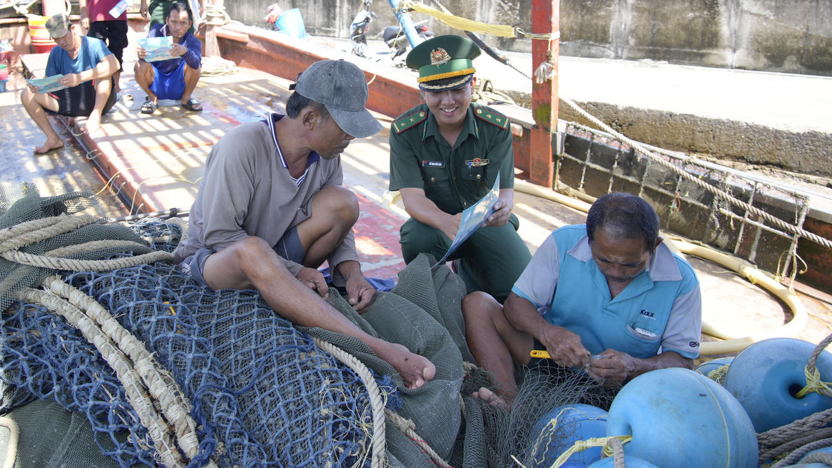 Cán bộ Đồn Biên phòng Gành Dầu phát tờ rơi cho chủ tàu, tài công nội dung liên quan đến chống khai thác IUU. (ảnh: Tiến Vinh)