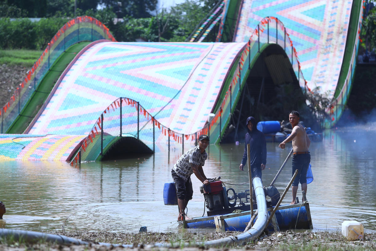 Người dân sử dụng máy bơm nước công suất lớn để 'giải cứu' cầu trượt.