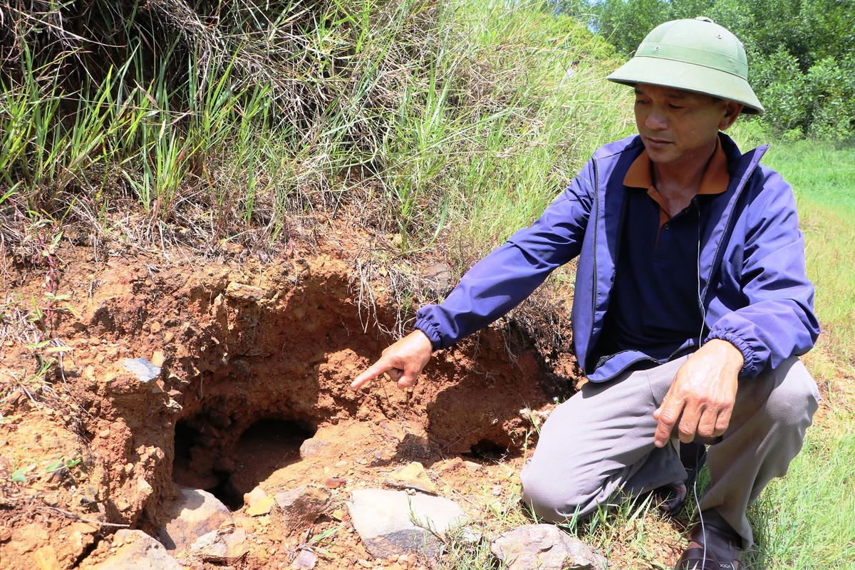 Người dân chỉ vị trí nước rò rỉ ở thân đập Phượng Hoàng, xã Đông Sơn (tỉnh Quảng Ngãi). Ảnh: Chí Đại