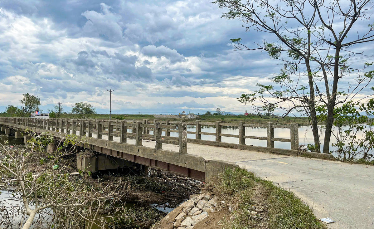 Vào mùa mưa bão, nước sông dâng cao, toàn bộ mặt cầu chìm trong dòng nước đục ngầu. Lúc ấy, việc lưu thông bị cấm tạm thời, nhưng ngay khi nước rút, người dân lại phải qua lại, bởi đây là tuyến huyết mạch duy nhất nối các thôn phía bên kia sông với trung tâm xã. Ảnh: Cẩm Kỳ
