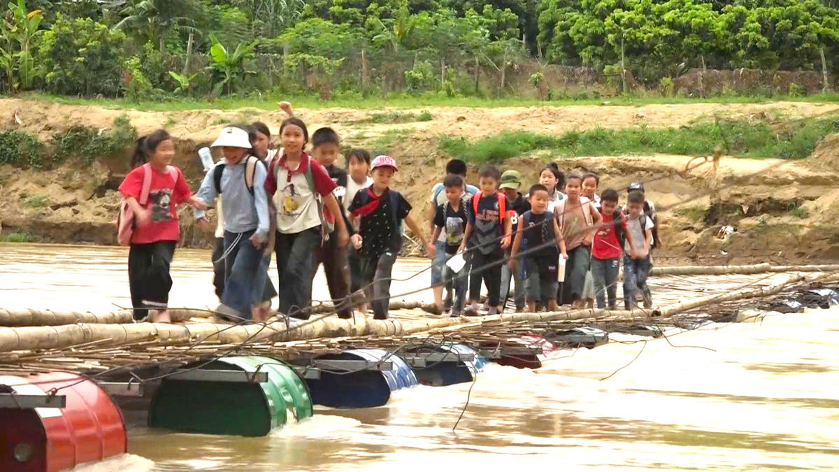 Học sinh trường Tiểu học Chiềng Sơ đi học qua cầu phao tạm. Ảnh: Cao Thiên - Dương Linh.