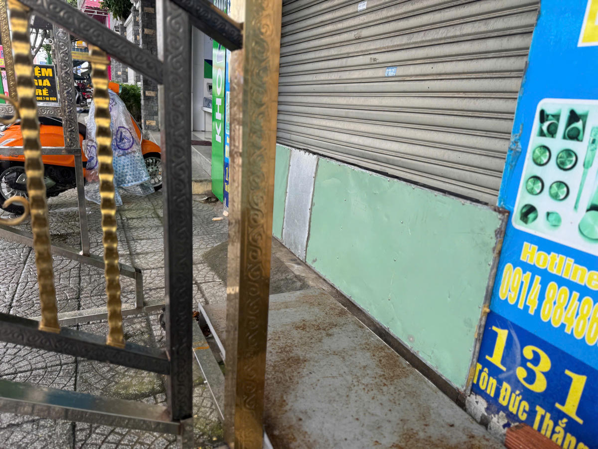 Cơ sở kinh doanh mặt tiền Tôn Đức Thắng dùng đồ chặn cửa để ngăn nước tràn vào khu mưa lớn, ngập nặng. Ảnh: Nguyễn Tú