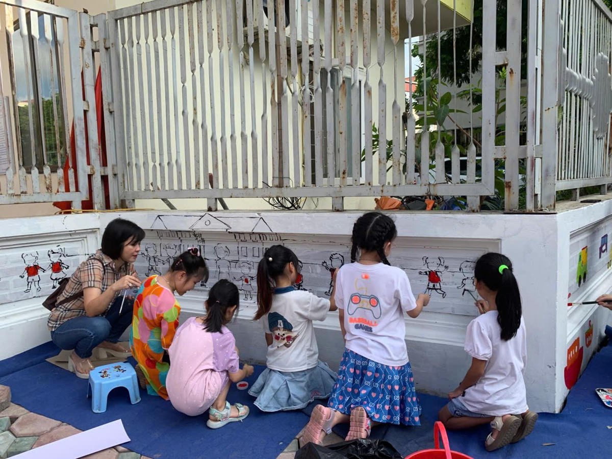 Các học sinh và phụ huynh trường tiểu học Vạn Phúc tham gia vẽ tranh tường làm đẹp khu vực trường học.