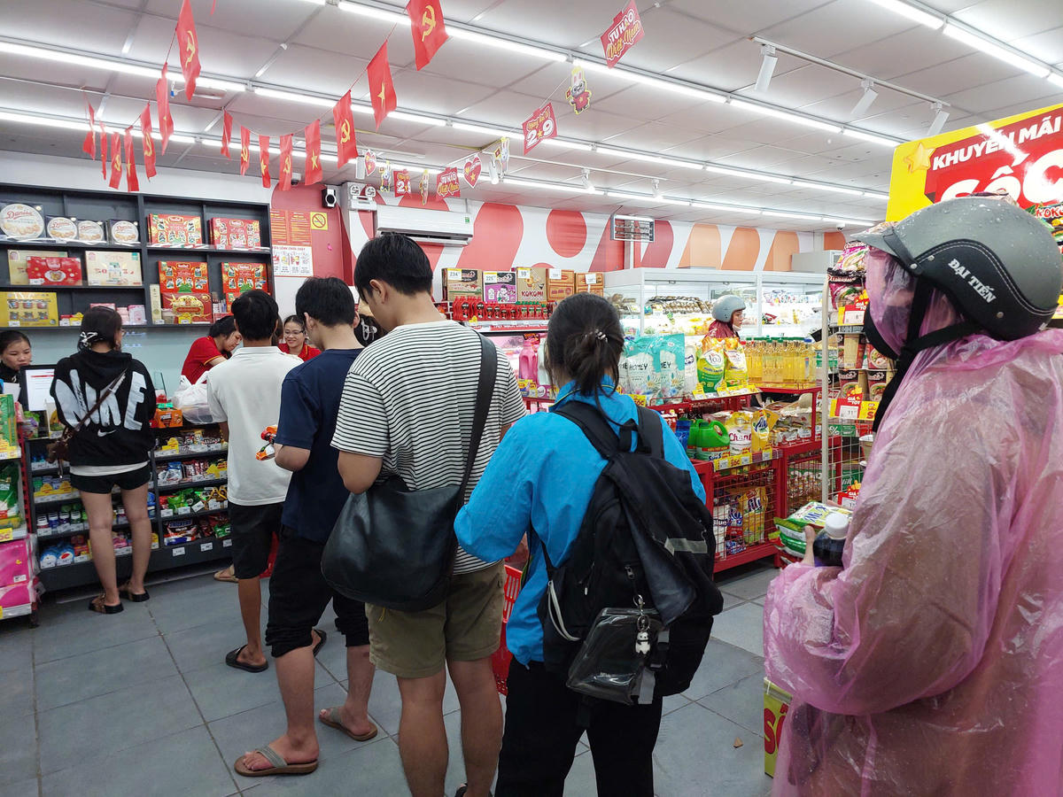 Người dân xếp hàng mua thực phẩm dự trữ đề phòng có thể xảy ra mưa lớn nhiều ngày tới. Ảnh: Tấn Thành.