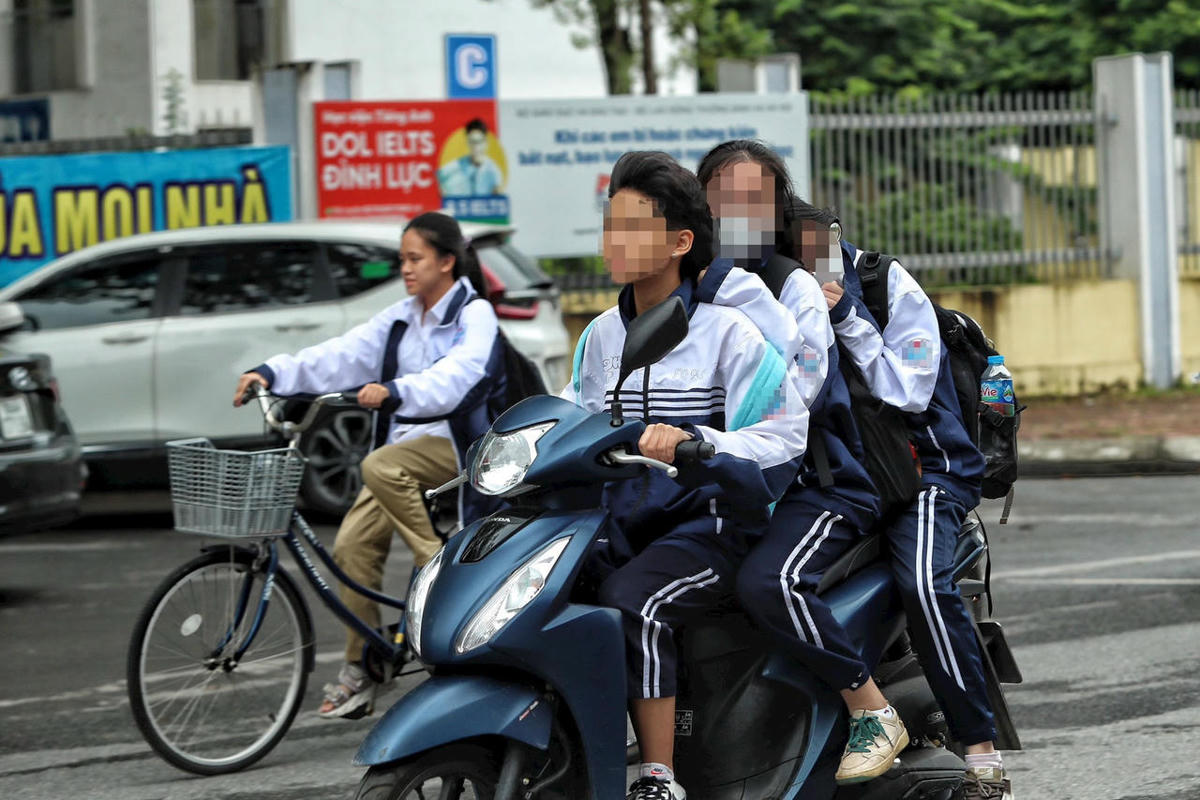 Học sinh mặc đồng phục chở 3, không đội mũ bảo hiểm khi tham gia giao thông. Ảnh: Lê Khánh.