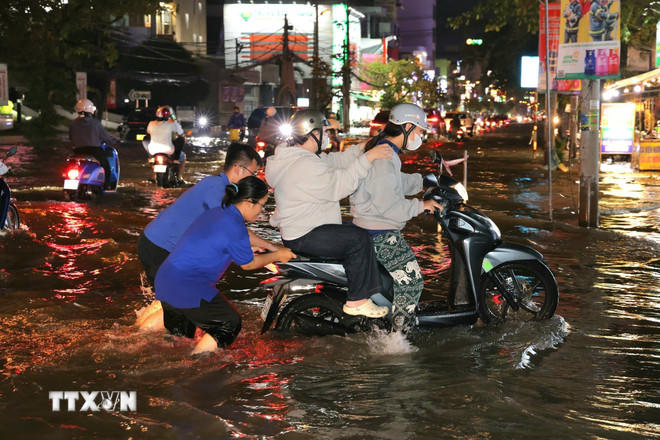 Sinh viên hỗ trợ người dân đẩy xe lên các điểm cao chờ nước rút. (Ảnh: Thanh Liêm/TTXVN)