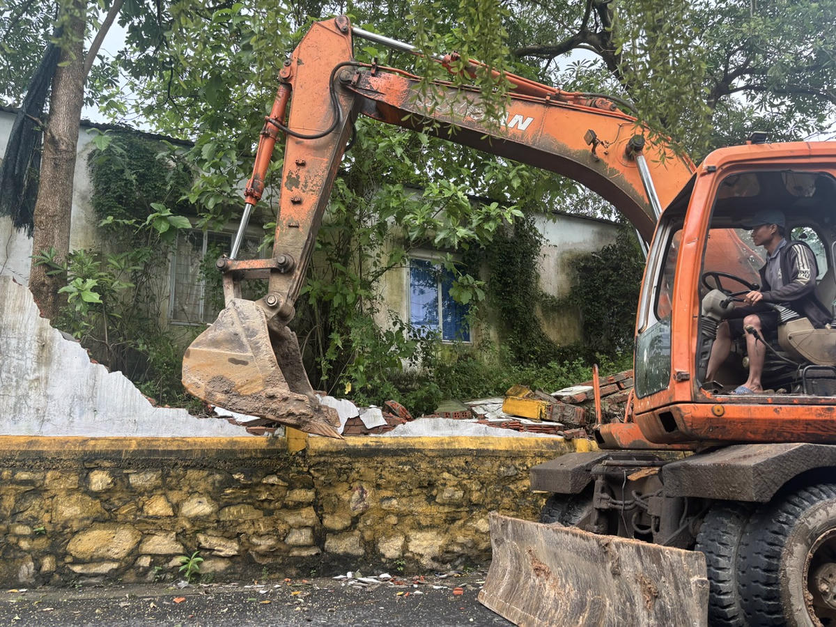 Phá dỡ bờ tường nghiêng, xuống cấp để đề phòng sập đổ gây nguy hiểm cho người dân. Ảnh: Nguyễn Tú.