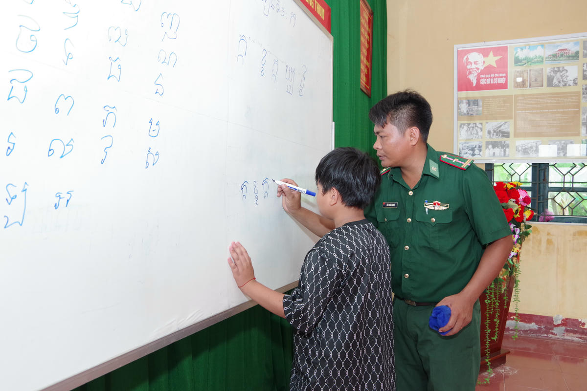 Thiếu tá Giang kiên trì hướng dẫn học sinh viết từng nét chữ. Ảnh: NVCC.