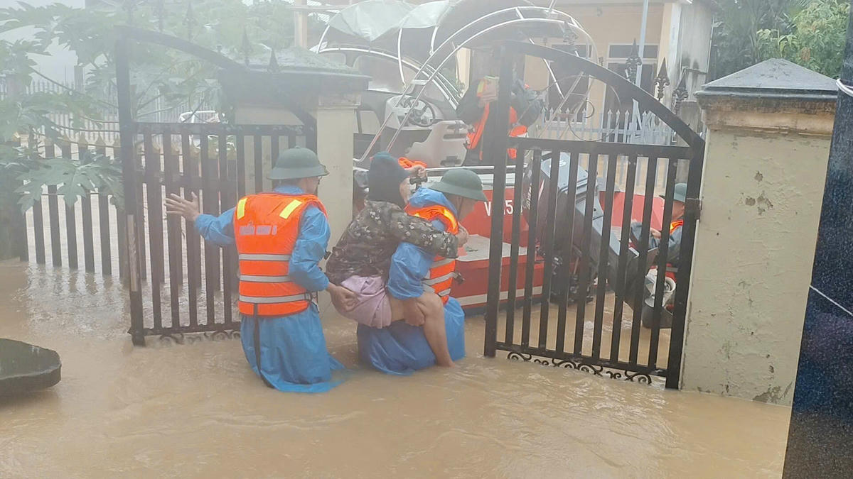 Lực lượng cứu cụ bà mắc kẹt trong nhà ngập nước. Ảnh: Quang Hùng.