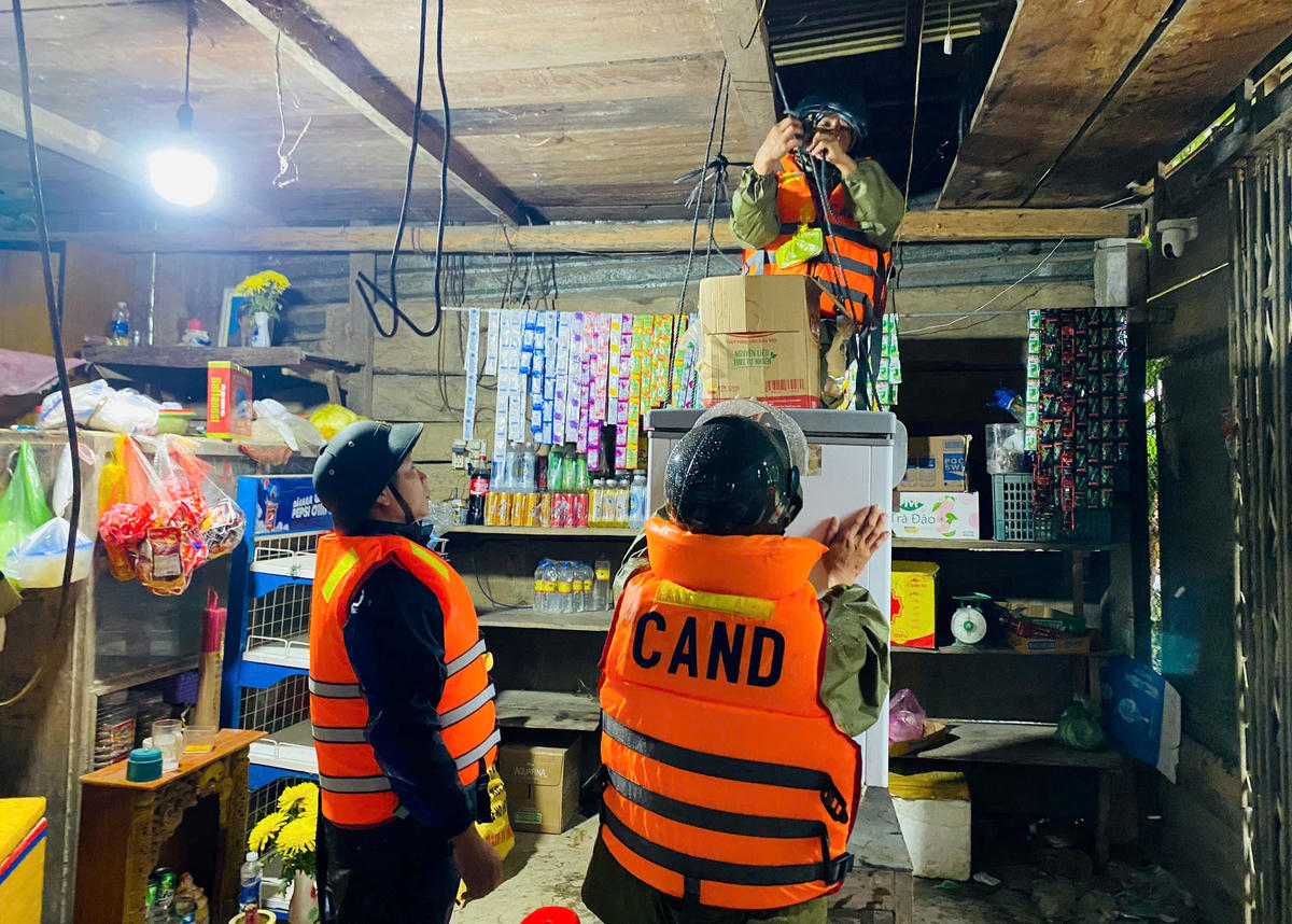 Lực lượng chức năng xã Thượng Đức giúp bà Võ Thị Tứ đưa đồ đạc trong nhà lên vị trí cao. Ảnh: T. Thành.