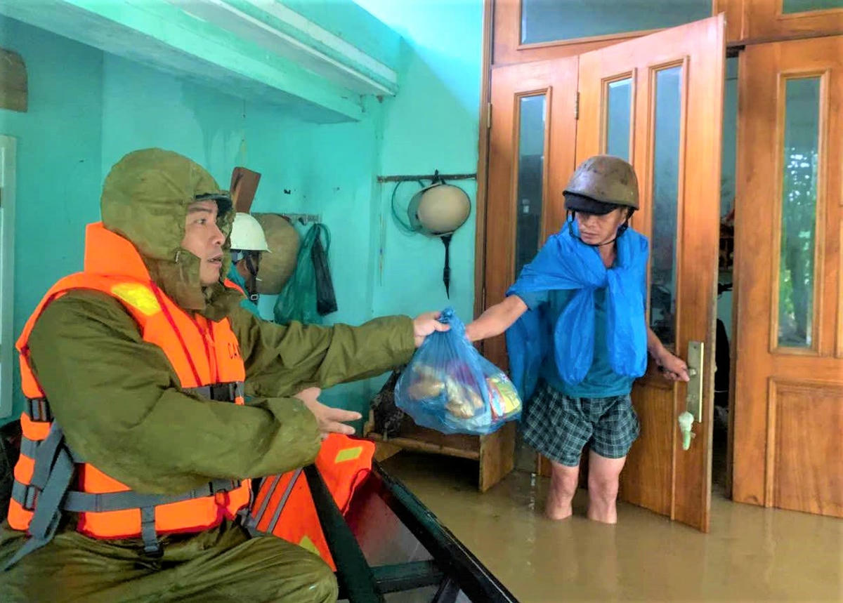 Các chiến sĩ Công an phường Điện Bàn Bắc đưa tận tay nhu yếu phẩm cho bà còn vùng lũ. Ảnh: CV.