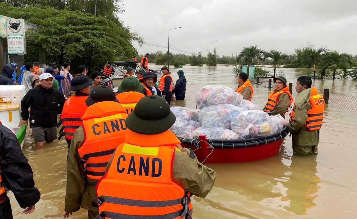 Công an băng mình trong lũ dữ cung cấp nhu yếu phẩm cho người dân. Ảnh CV.