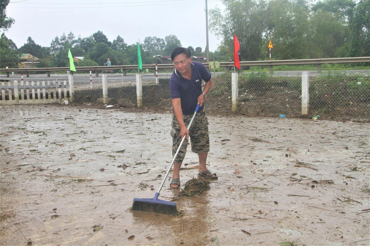 Ông Đặng Văn Sen đang dọn dẹp bùn đất trước sân nhà. Ảnh: Chí Đại. 