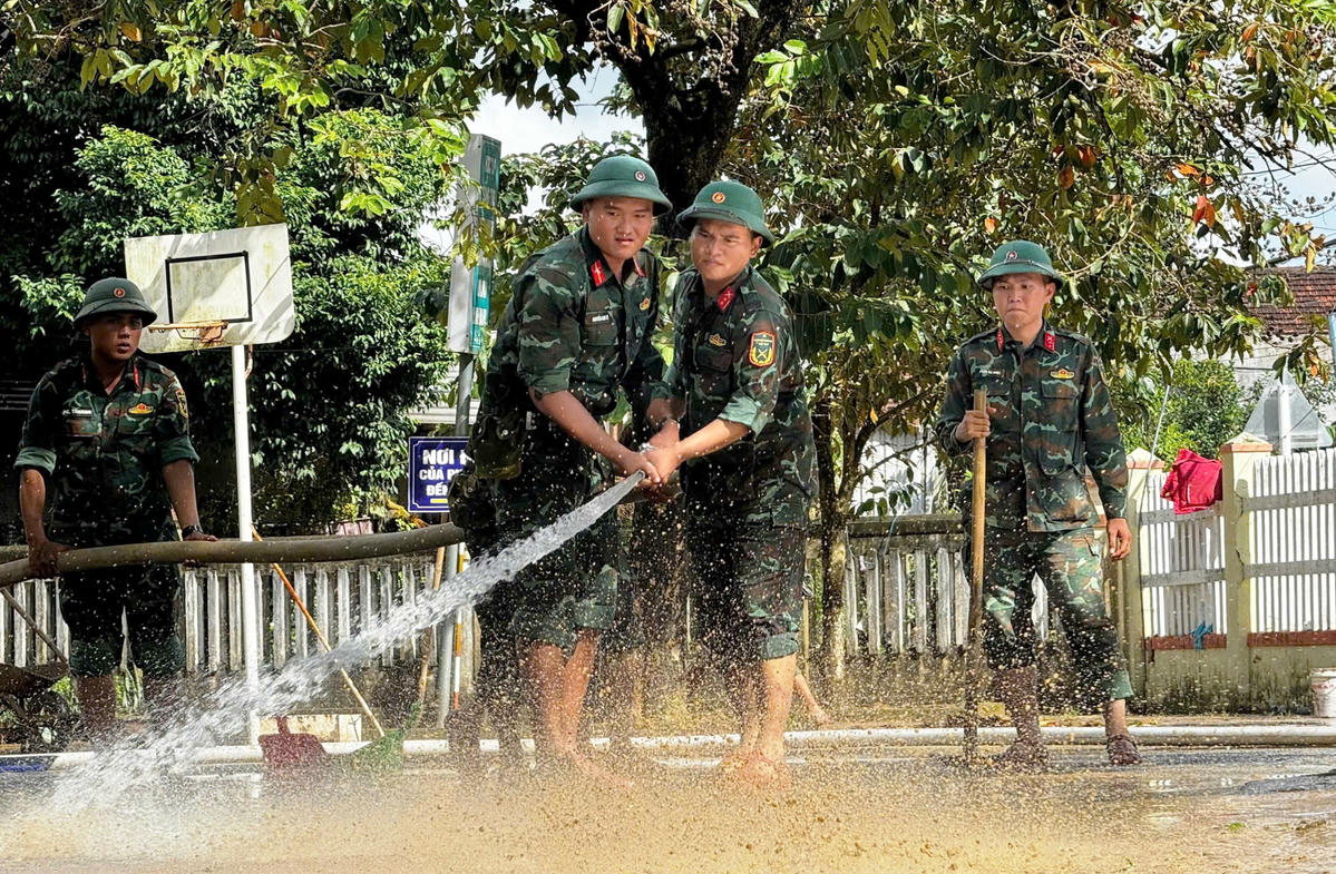 Bộ đội giúp người dân dọn dẹp nhà cửa bị ngập bùn sau lũ tại xã Bình Minh, tỉnh Quảng Ngãi. Ảnh: Chí Đại.