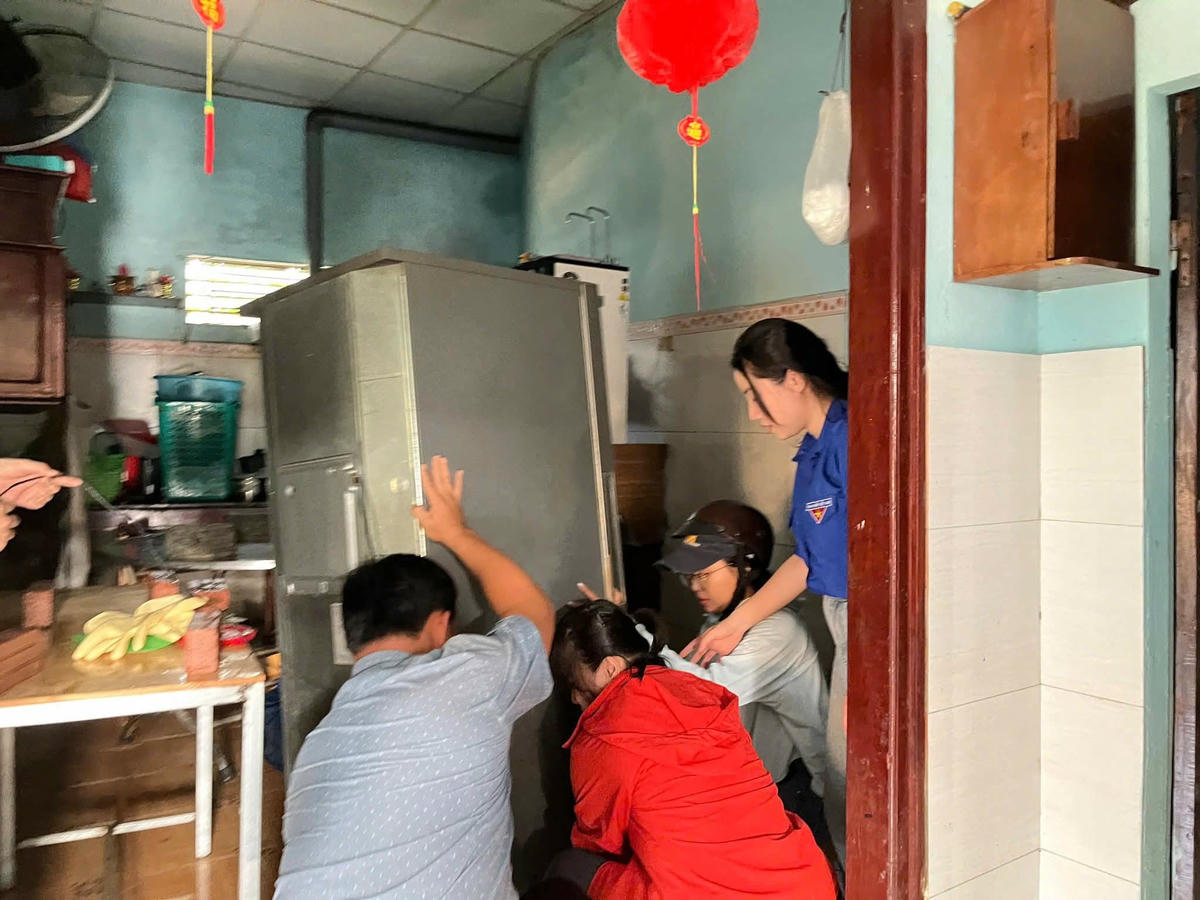 Lực lượng Đoàn viên giúp người dân hạ đồ đạc sau khi chạy lũ. Ảnh: Cẩm Vân.