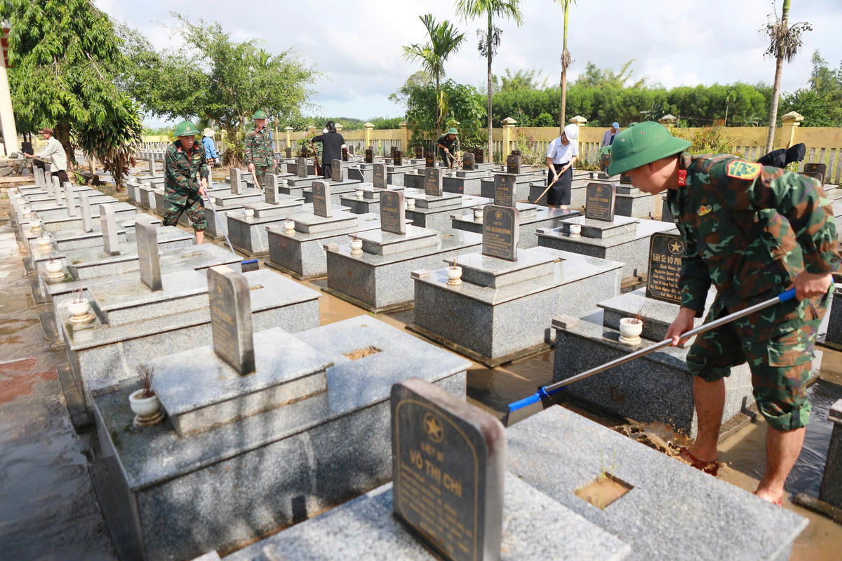 Lực lượng quân đội, người dân dọn dẹp bùn đất sau khi lũ rút xuống tại Nghĩa trang Liệt sĩ xã Bình Minh. Ảnh: CV.