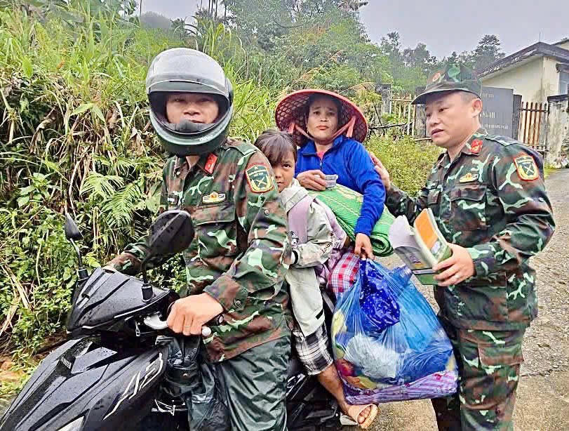 Lực lượng chức năng hỗ trợ người dân xã Tây Trà Bồng đi sơ tán. Ảnh: CV.