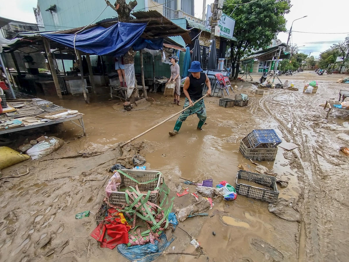 Người dân xã Đại Lộc đang dọn dẹp bùn đất ở chợ Ái Nghĩa. Ảnh: CV.