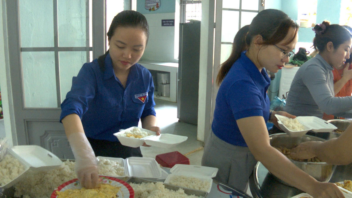 Các bạn đoàn viên, cô giáo Trường mầm non Hoa Mai nấu cơm đưa miễn phí cho bà con vùng cô lập. Ảnh: CV.