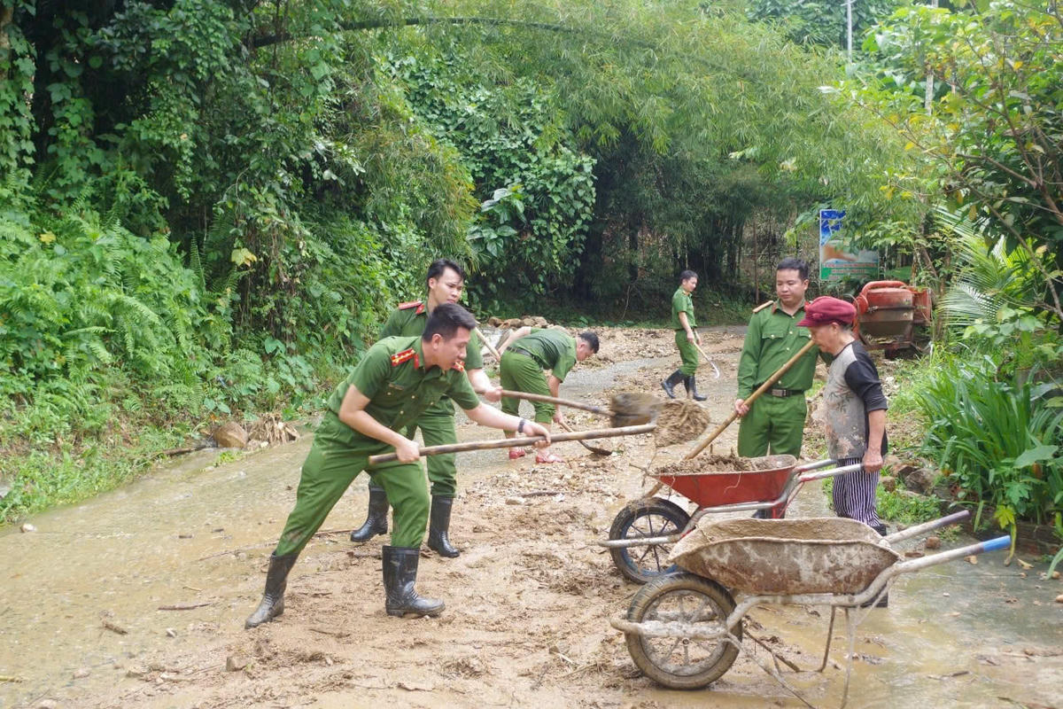 Lực lượng Công an xã Nam Trà My cùng người dân dọn đất đá sạt lở tràn xuống mặt đường. Ảnh: CV.