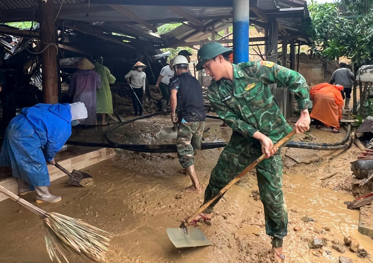 Cán bộ Đồn Biên phòng Tr'hy dọn dẹp bùn đất nhà người dân thôn A râng, xã Hùng Sơn. Ảnh: CV.