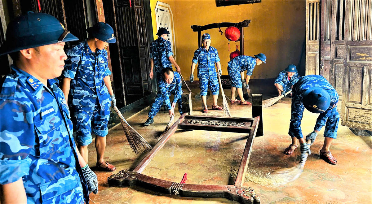 &nbsp;Cán bộ, chiến sĩ Bộ Tư lệnh Vùng Cảnh sát biển 2 giúp người dân phường Hội An Tây dọn dẹp bùn đất trong nhà. Ảnh: CV.