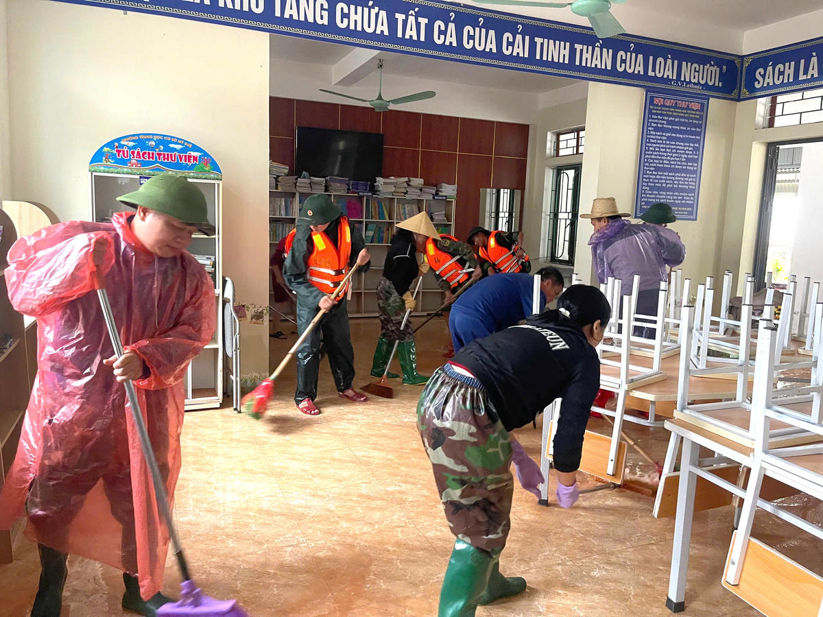 Lực lượng quân sự và tập thể giáo viên Trường THCS Mỹ Duệ (xã Cẩm Duệ, Hà Tĩnh) tập trung dọn dẹp trường lớp. Ảnh: ĐS.