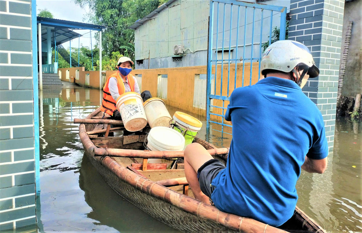 Người dân sử dụng ghe đi lại khu dân cư ngập nước. Ảnh: Nguyễn Tín.