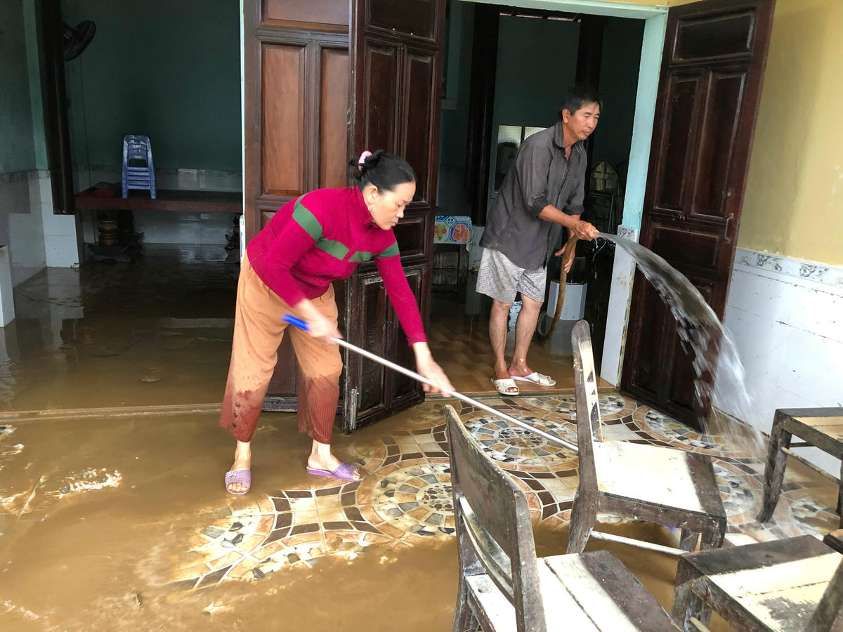 Bà Nguyễn Thị Trinh (áo đỏ) cùng người thân dọn vệ sinh nhà cửa sau khi nước lũ rút xuống. Ảnh: Tấn Thành. 