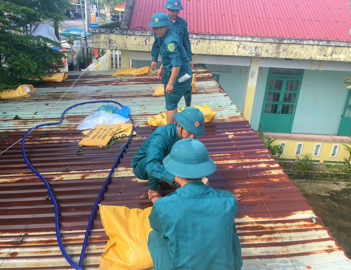 Lực lượng chức năng xã Thăng An đang bơm túi nước chằng chống trên mái nhà. Ảnh: CV.