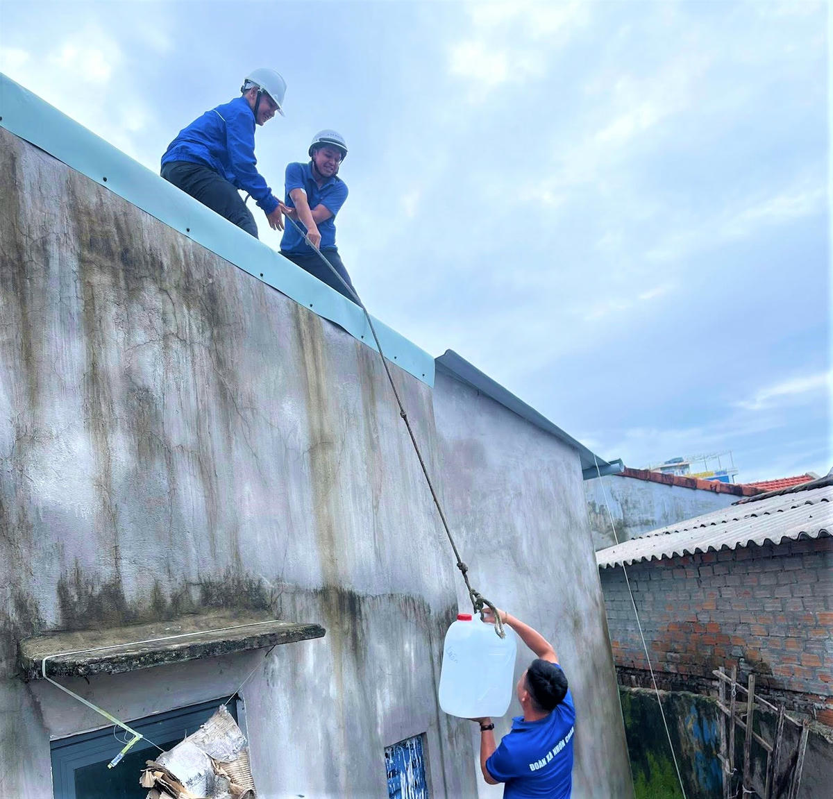 Lực lượng thanh niên xã đảo Nhơn Châu dùng canh nhựa chứa nước chằng chống mái nhà. Ảnh: CV.
