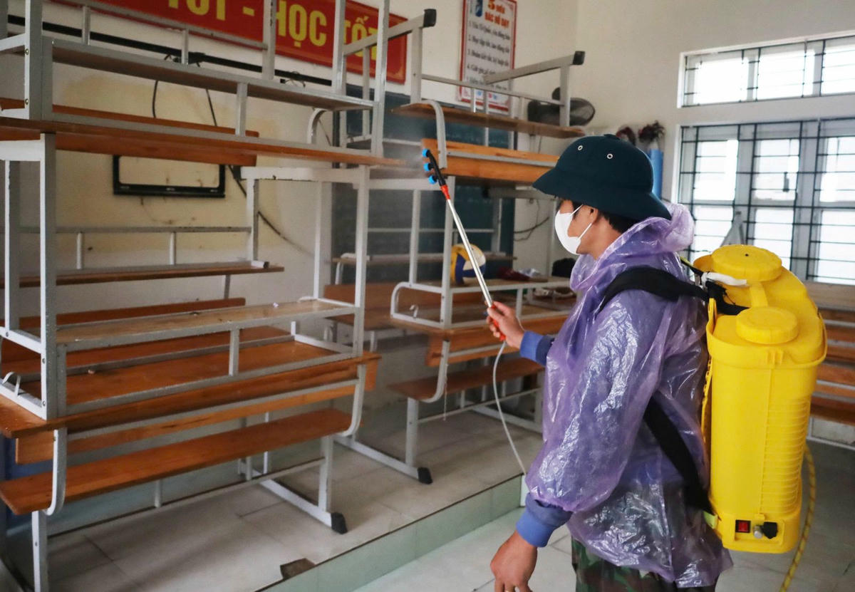 Lực lượng y tế phun hóa chất khử khuẩn bằng Cloramin B tại trường THCS Mỹ Duệ. Ảnh: NT.